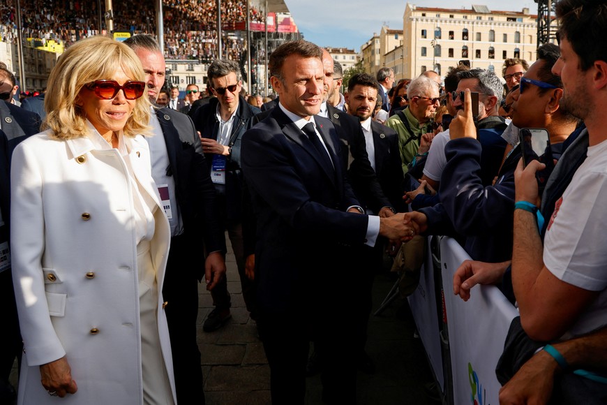 France's President Emmanuel Macron shakes hands with spectators next to his wife Brigitte Macron during the Olympic Flame arrival ceremony at the Vieux-Port (Old Port), ahead of the Paris 2024 Olympic and Paralympic Games, in Marseille, southeastern France, on May 8, 2024.  LUDOVIC MARIN/Pool via REUTERS