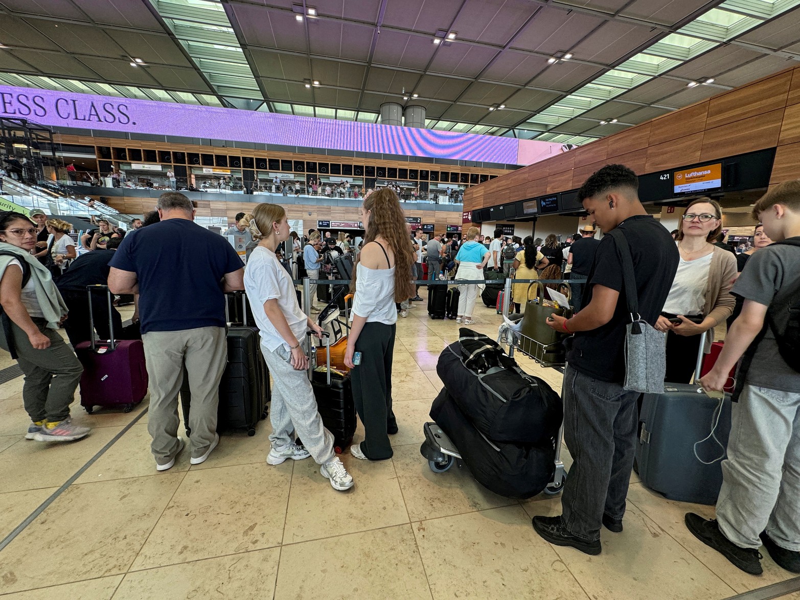 La gente espera sus vuelos tras una interrupción mundial de TI en el aeropuerto BER de Berlín, Alemania