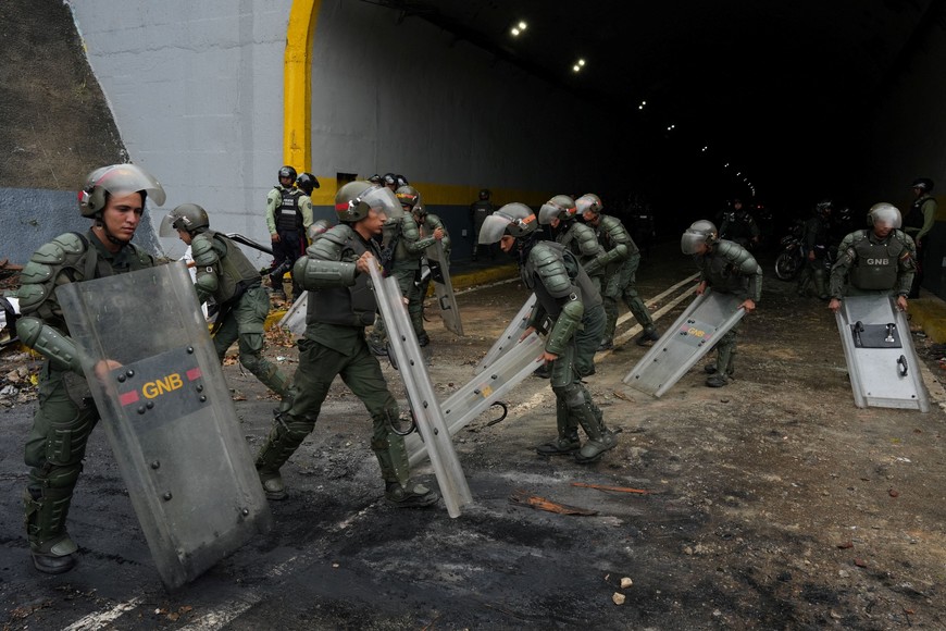 Members of the Bolivarian National Guard of Venezuela use their shields to clean an avenue after a protest from supporters of Venezuelan opposition following the announcement by the National Electoral Council that Venezuela's President Nicolas Maduro won the presidential election, in Caracas, Venezuela July 29, 2024. REUTERS/Alexandre Meneghini