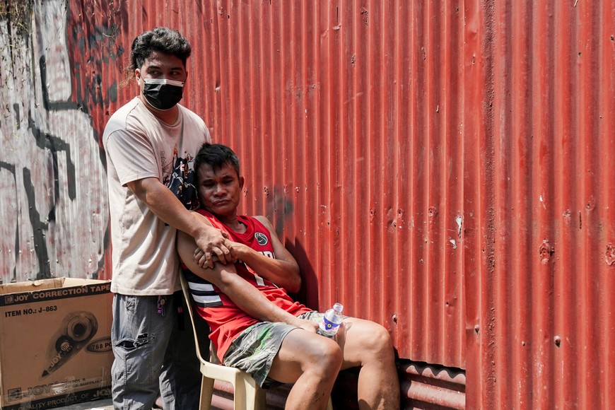 A man reacts while sitting outside a burned building in Manila, Philippines, August 2, 2024. REUTERS/Lisa Marie David