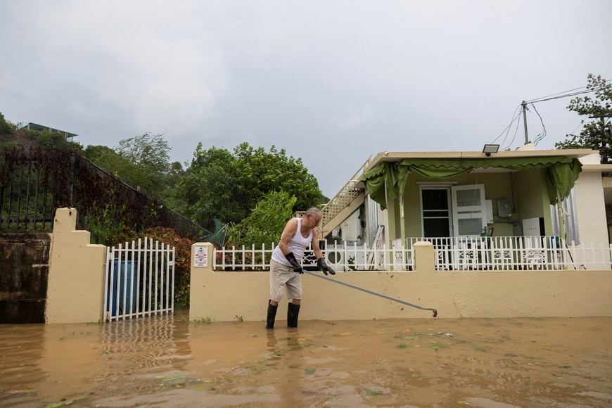 Irvin Morales, 80, uses a rake to unclog a drainage in the aftermath of Tropical Storm Ernesto in Fajardo, Puerto Rico August 14, 2024.  REUTERS/Ricardo Arduengo