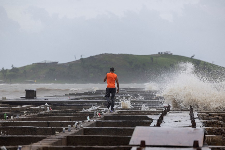 A man walks as waves crash on a damaged pier in the aftermath of Tropical Storm Ernesto in Humacao, Puerto Rico August 14, 2024.  REUTERS/Ricardo Arduengo