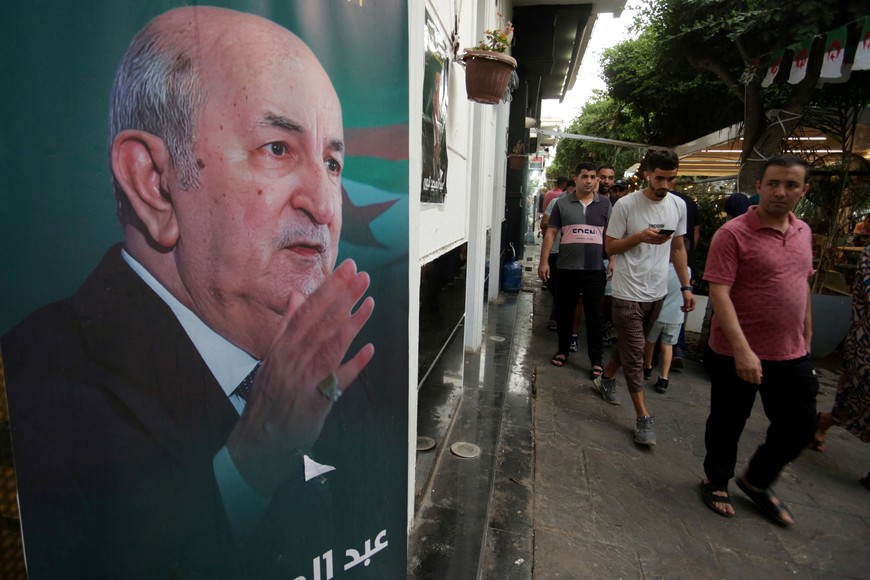 People walk past an electoral poster of Algeria's President Abdelmadjid Tebboune, after the authorities declared him winner of the country's presidential election, in Algiers, Algeria September 8, 2024. REUTERS/Ramzi Boudina