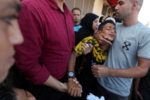 A boy is comforted as he mourns near the body of his father and other Palestinians, who were killed in an Israeli strike, amid the Israel-Hamas conflict, at Al-Aqsa Martyrs Hospital in Deir Al-Balah in the central Gaza Strip, October 9, 2024. REUTERS/Ramadan Abed     TPX IMAGES OF THE DAY