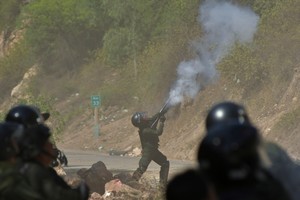 A police officer shoots tear gas at supporters of Bolivia's former President Evo Morales as police attempt to dismantle a blockade set in protest of the government of President Luis Arce, in Parotani, Bolivia October 25, 2024. REUTERS/Patricia Pinto