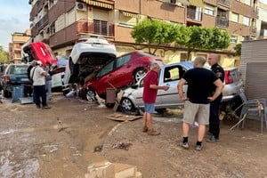 People stand alongside cars piled up on a residential street in the aftermath of torrential rains that caused flooding, in Alfafar, Valencia region, Spain October 31, 2024. REUTERS/Miguel Pereira