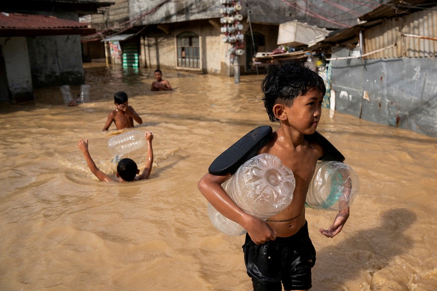 Children play along a flooded street following super typhoon Man-Yi, in Cabanatuan, Nueva Ecija, Philippines, November 18, 2024. REUTERS/Lisa Marie David TPX IMAGES OF THE DAY