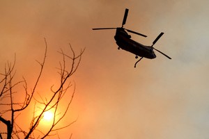 A helicopter flies over the Palisades Fire, one of several simultaneous blazes that have ripped across Los Angeles County, along Mandeville Canyon, in the Encino neighborhood of Los Angeles, California, U.S., January 11, 2025. REUTERS/Daniel Dreifuss     TPX IMAGES OF THE DAY