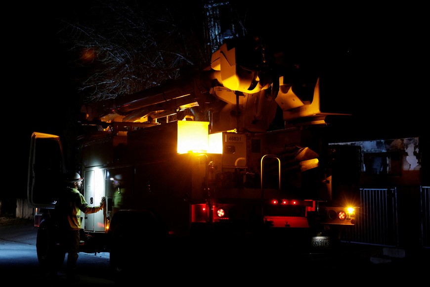 An electric worker stands by his truck, as the Eaton Fire continues to burn, outside a devastated home in Altadena, California, U.S. January 13, 2025. REUTERS/Shannon Stapleton