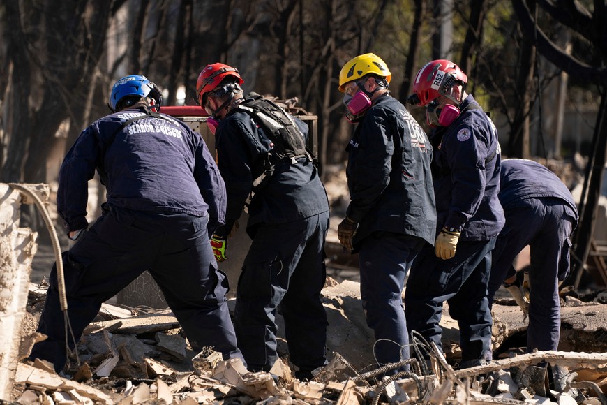 A search and rescue team searches the remains of a home burned by the Palisades Fire, in the Pacific Palisades neighborhood in Los Angeles, California, U.S. January 14, 2025. REUTERS/David Ryder