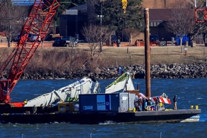 A crane retrieves part of the wreckage from the Potomac River, in the aftermath of the collision of American Eagle flight 5342 and a Black Hawk helicopter that crashed into the river, by the Ronald Reagan Washington National Airport, in Arlington, Virginia, U.S., February 4, 2025.  REUTERS/Eduardo Munoz