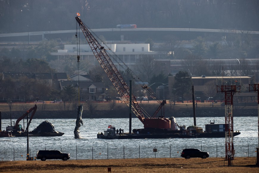 A crane retrieves part of the wreckage from the Potomac River, in the aftermath of the collision of American Eagle flight 5342 and a Black Hawk helicopter that crashed into the river, by the Ronald Reagan Washington National Airport, in Arlington, Virginia, U.S., February 4, 2025.  REUTERS/Eduardo Munoz
