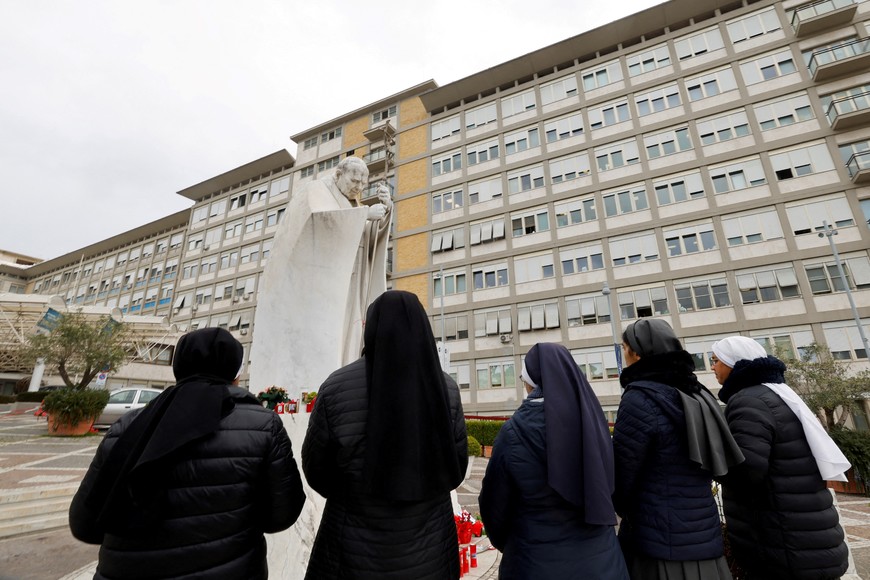 Nuns pray in front of the statue of late Pope John Paul II outside the Gemelli Hospital where Pope Francis is admitted for treatment, in Rome, Italy, February 24, 2025. REUTERS/Ciro De Luca     TPX IMAGES OF THE DAY