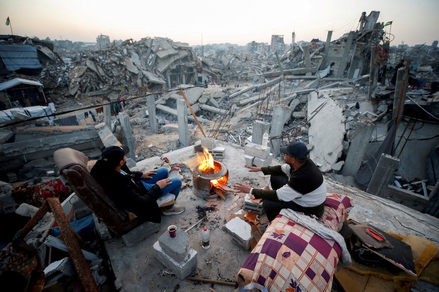 Palestinians sit next to a fire among the rubble of buildings destroyed during the Israeli offensive, amid a ceasefire between Israel and Hamas, at Jabalia refugee camp, northern Gaza Strip, February 17, 2025. REUTERS/Mahmoud Issa     TPX IMAGES OF THE DAY     REFILE - CORRECTING FROM "AMONG RUBBLE OF DESTROYED BUILDINGS DURING THE ISRAELI OFFENSIVE" TO "AMONG THE RUBBLE OF BUILDINGS DESTROYED DURING THE ISRAELI OFFENSIVE".