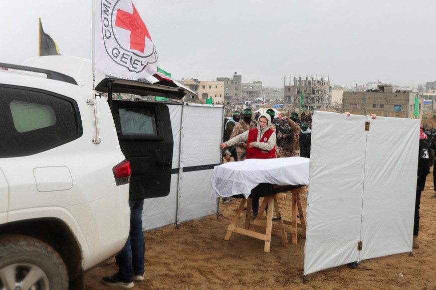 A member of the Red Cross stands near a coffin during the handover of deceased hostages Oded Lifschitz, Shiri Bibas and her two children Kfir and Ariel Bibas, seized during the deadly October 7, 2023 attack, to the Red Cross, as part of a ceasefire and hostages-prisoners swap deal between Hamas and Israel, in Khan Younis in the southern Gaza Strip, February 20, 2025. REUTERS/Ramadan Abed     TPX IMAGES OF THE DAY