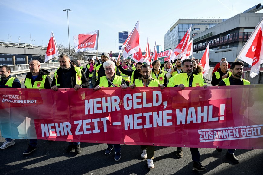 Workers hold a banner as they demonstrate during a 24-hour strike at the Frankfurt Airport called by the German trade union Verdi over a wage dispute in Frankfurt, Germany March 10, 2025. The banner reads, "More money, more time - my choice!". REUTERS/Jana Rodenbusch