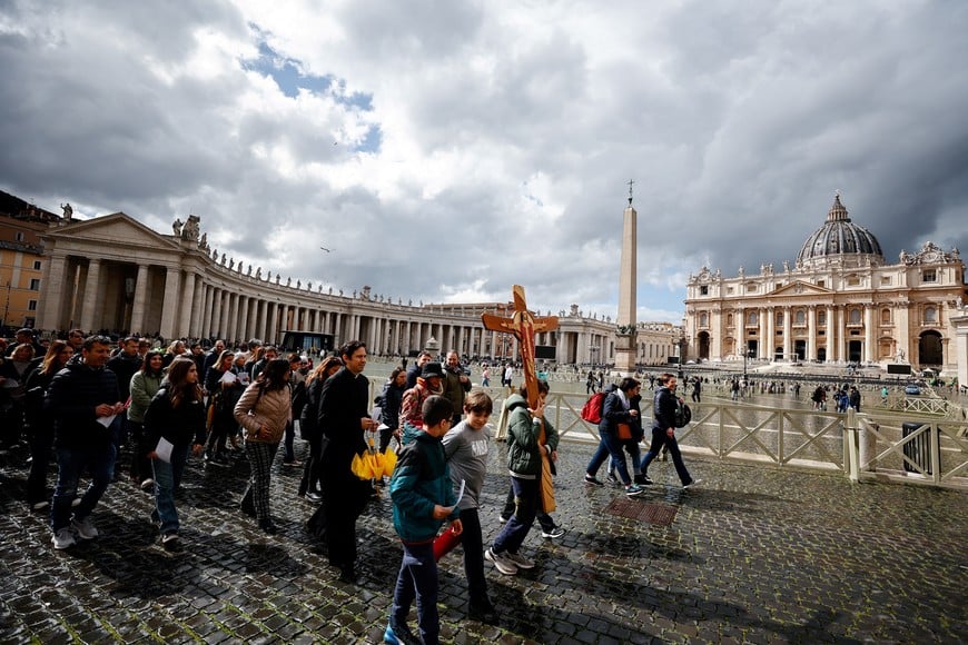 A child pilgrim carries a wooden cross in St Peter's Square at the Vatican, as Pope Francis continues treatment in Rome's Gemelli hospital, March 16, 2025. REUTERS/Vincenzo Livieri