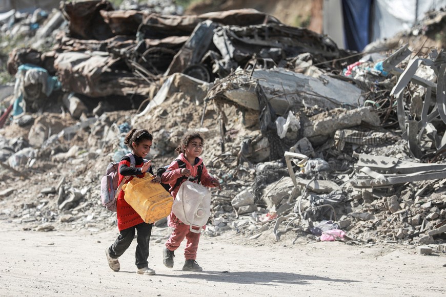 Palestinian children walk past rubble as people make their way to flee their homes, after the Israel army issued evacuation orders for a number of neighborhoods, following heavy Israeli strikes, in Beit Lahiya in the northern Gaza Strip March 18, 2025. REUTERS/Abd Elhkeem Khaled