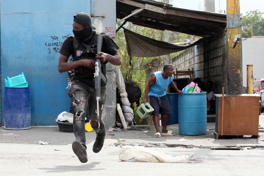 A police officer runs during a clash with gangs as a resident of the Delmas 30 neighborhood flees his home due to gang violence, in Port-au-Prince, Haiti, February 26, 2025. REUTERS/Fildor Pq Egeder     TPX IMAGES OF THE DAY