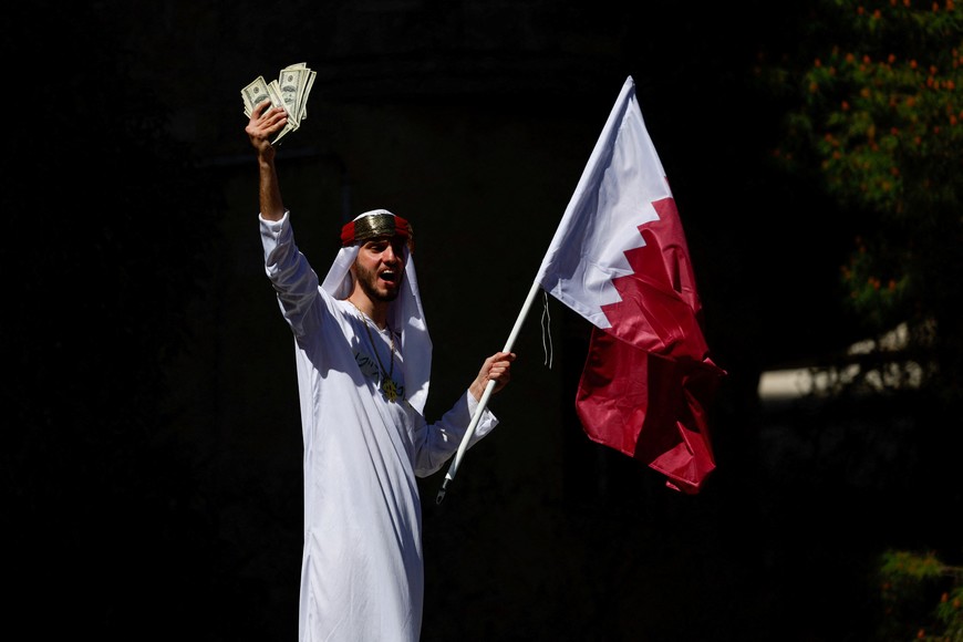 A demonstrator holds representations of U.S. dollar bills and a Qatari flag, at a rally against Israeli Prime Minister Benjamin Netanyahu and his government, where protesters demand the release of all hostages from Gaza, near Netanyahu's residence in Jerusalem, March 19, 2025. REUTERS/Ammar Awad