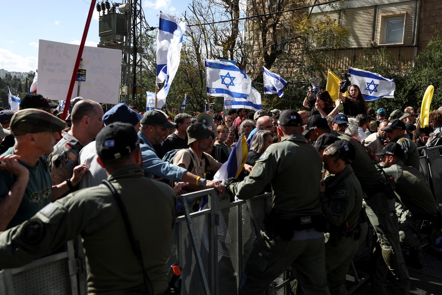 Police officers stand behind metal barriers, as people attend a rally, against the Israeli government and Israeli Prime Minister Benjamin Netanyahu, and demanding the release of all hostages from Gaza, near the Netanyahu's residence in Jerusalem, March 19, 2025. REUTERS/Ronen Zvulun