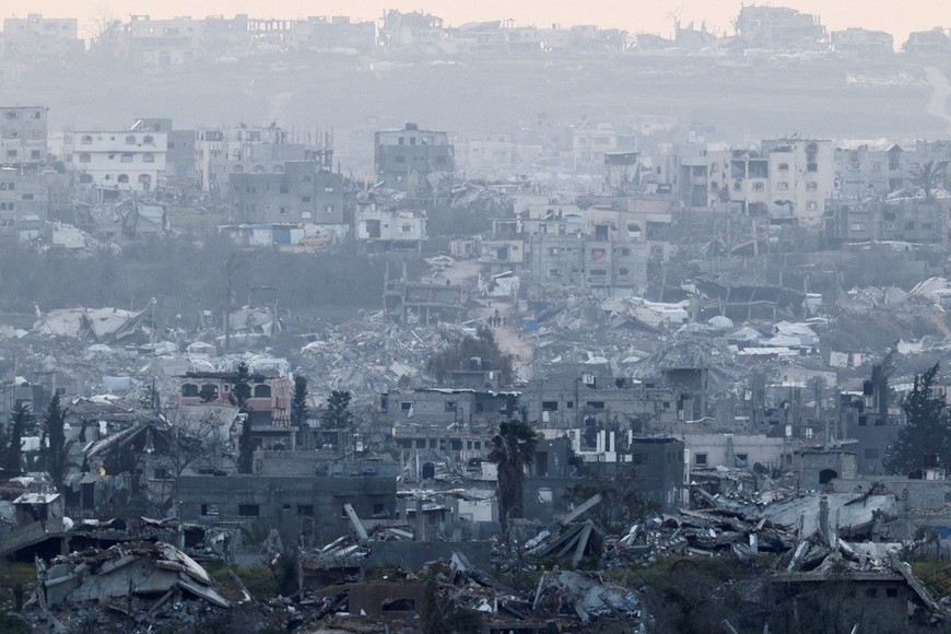 People walk among destroyed buildings in Gaza, as viewed from the Israel-Gaza border, March 20, 2025. REUTERS/Amir Cohen