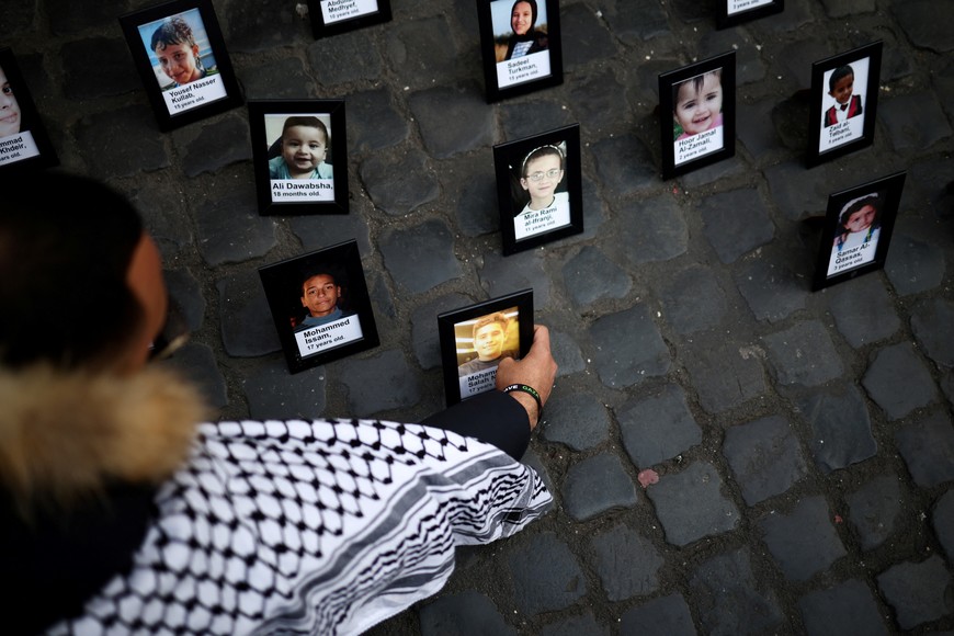 A man places photographs of people who died during the ongoing conflict between Israel and Hamas during a protest to show support for Palestinians in Gaza, near the Pantheon in Rome, Italy, March 20, 2025. REUTERS/Guglielmo Mangiapane