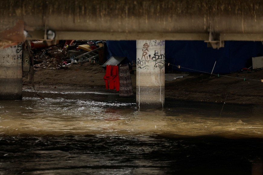 Belongings of people, who live under a bridge, are close to the water of the Manzanares river, with unusually high levels after weeks of rain in Madrid, Spain, March 21, 2025. REUTERS/Susana Vera
