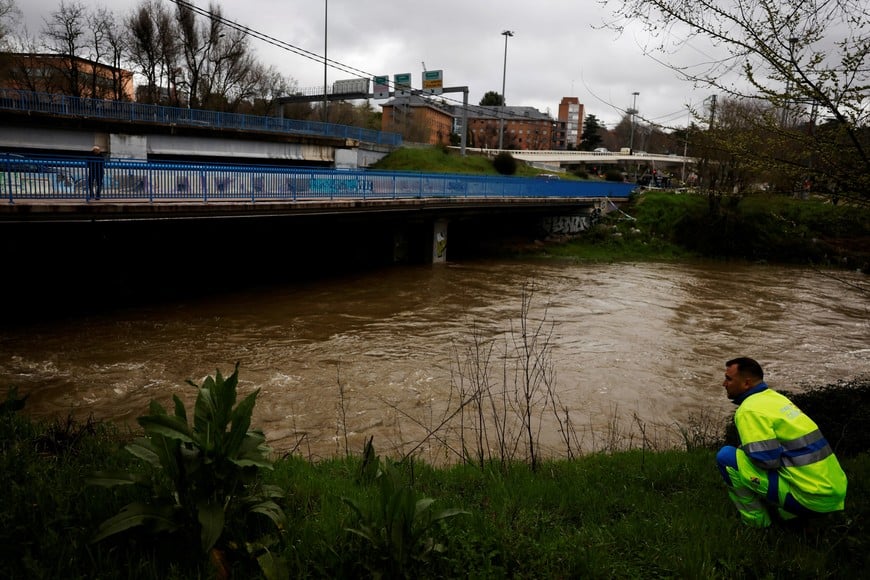 A municipal worker checks the unusually high levels of water of the Manzanares river after weeks of rain in Madrid, Spain, March 21, 2025. REUTERS/Susana Vera