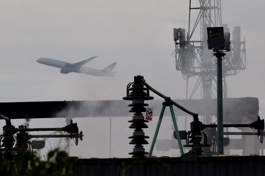 A plane takes off, as smoke rises from an area of an electrical substation a day after it caught fire and wiped out power at Heathrow International Airport, near London, Britain, March 22, 2025. REUTERS/Carlos Jasso     TPX IMAGES OF THE DAY
