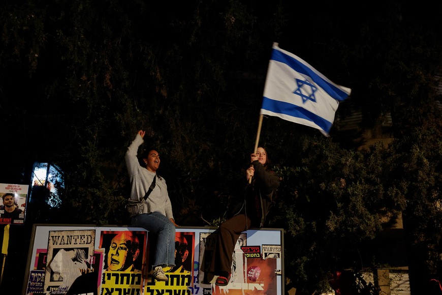A demonstrator waves an Israeli flag, during a protest against moves by the Israeli government to fire the Attorney General Gali Baharav Miara and the dismissal of top security agency chief, Ronen Bar, near Israeli Prime Minister Benjamin Netanyahu's residence in Jerusalem, March 24, 2025. REUTERS/Ammar Awad