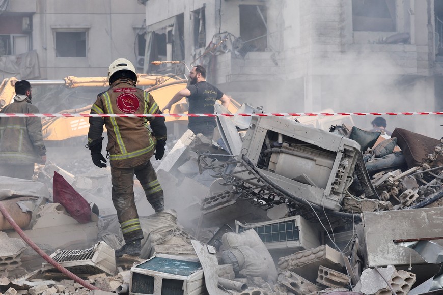 Firefighters and a member of the Lebanese Civil Defense work at the site of an Israeli strike, in Beirut southern suburbs, Lebanon, March 28, 2025. REUTERS/Mohamed Azakir