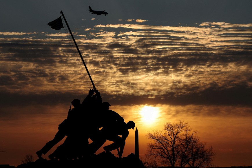 A plane flies overhead as the sun rises behind the Washington Monument and the U.S. Marine Corps War Memorial (Iwo Jima Memorial) on the first day of spring in Arlington, Virginia, U.S., March 20, 2025. REUTERS/Kevin Lamarque     TPX IMAGES OF THE DAY