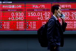 FILE PHOTO: A man walks past an electronic board displaying Japan's 10-year government bonds level, the current Japanese Yen exchange rate against the U.S. dollar and Nikkei share average, outside a brokerage in Tokyo, Japan, October 31, 2023. REUTERS/Kim Kyung-Hoon/File Photo