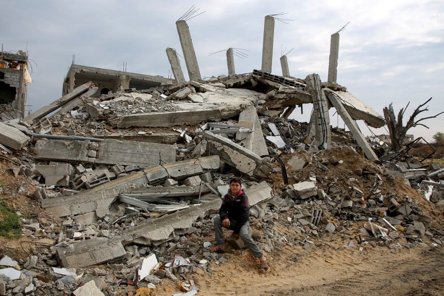 Palestinian boy Nezar Abdel Ghafour, who was injured due to an ordnance explosion, poses in front of the rubble of a destroyed building, in Khan Younis in the southern Gaza Strip, February 10, 2025. REUTERS/Hatem Khaled