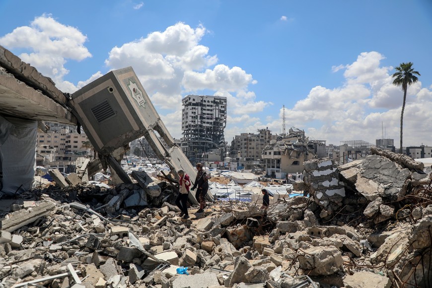 (250417) -- GAZA, 17 abril, 2025 (Xinhua) -- Imagen del 15 de abril de 2025 de palestinos caminando en medio de los escombros de edificios destruidos, en la Ciudad de Gaza. Las autoridades de Salud de Gaza anunciaron el miércoles que al menos 25 personas murieron y otras 89 resultaron heridas en Gaza en las últimas 24 horas. (Xinhua/Rizek Abdeljawad) (da) (ra) (ce)