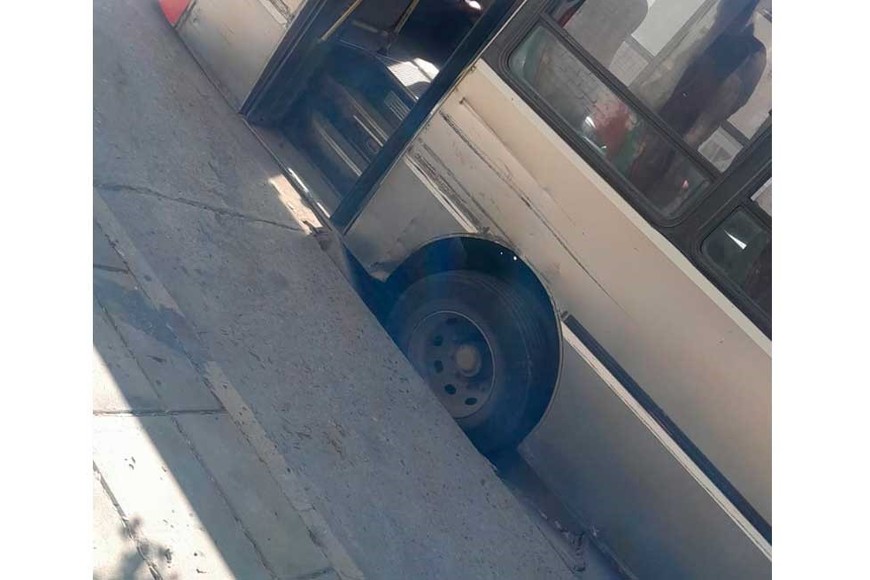 El colectivo con su rueda trasera derecha dentro del pozo.