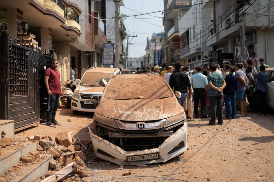 People stand next to a damaged vehicle in a neighbourhood, following Pakistan's military operation against India, in Rehari, Jammu, May 10, 2025. REUTERS/Adnan Abidi