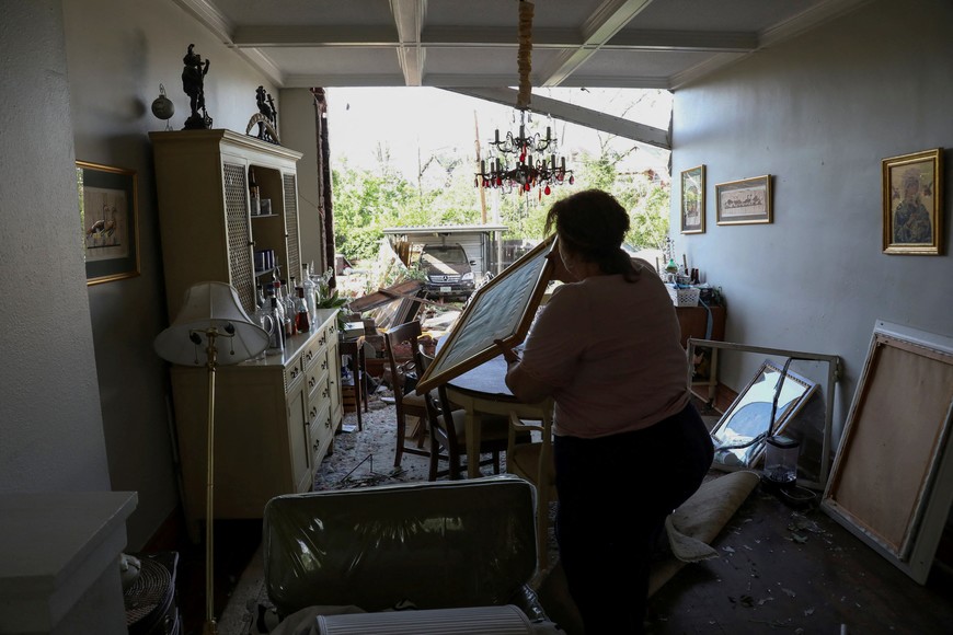 A woman salvages artwork from her dining room after a tornado tore off the back wall of her home in St. Louis, Missouri,U.S. May 16, 2025. REUTERS/Lawrence Bryant