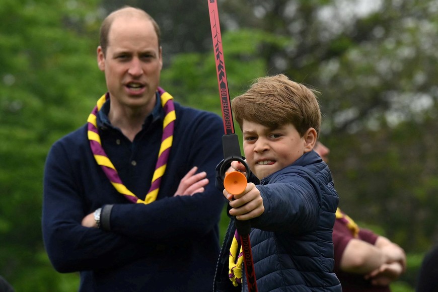 Britain's Prince George of Wales tries his hand at archery as Britain's Prince William, Prince of Wales, watches him, while taking part in the Big Help Out, during a visit to the 3rd Upton Scouts Hut in Slough, west of London, Britain, May 8, 2023. Daniel Leal/Pool via REUTERS