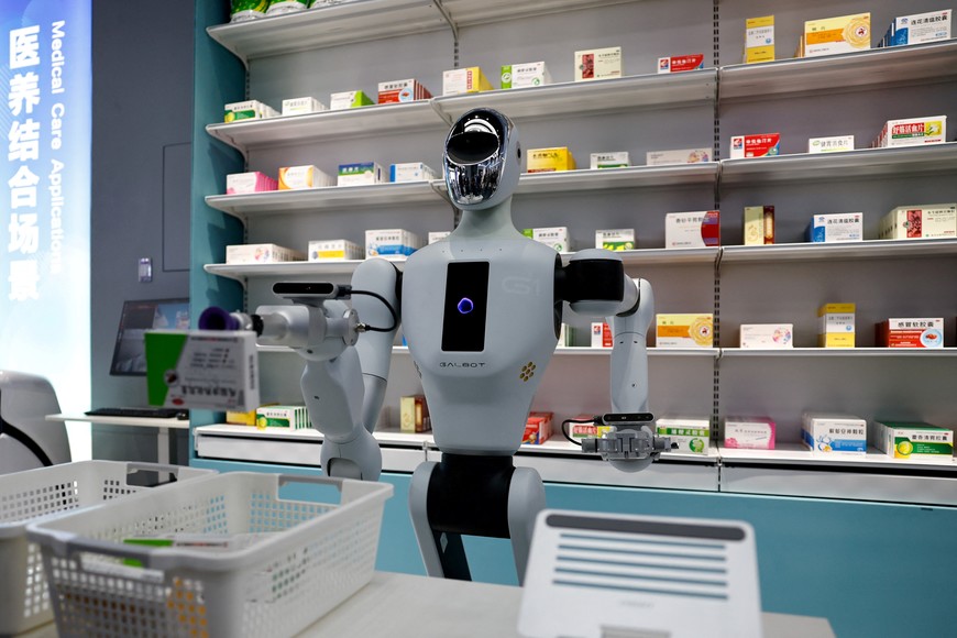 A humanoid robot Galbot G1 takes a medicine box off a shelf simulating a pharmacy as a demonstration at the robotics exhibition centre Robot World, during an organised media tour to Beijing Robotics Industrial Park, in Beijing Economic-Technological Development Area, also known as Beijing E-Town, in China May 16, 2025. REUTERS/Tingshu Wang