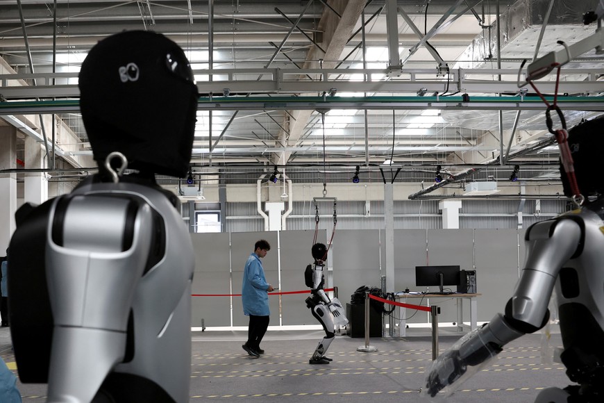 A humanoid robot walks as employees conduct tests on the robots, on the production line at the AgiBot factory in Shanghai, China March 20, 2025. REUTERS/Florence Lo     TPX IMAGES OF THE DAY