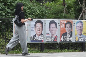 Una mujer camina frente a carteles de campaña de los candidatos presidenciales, en Seúl. Xinhua.