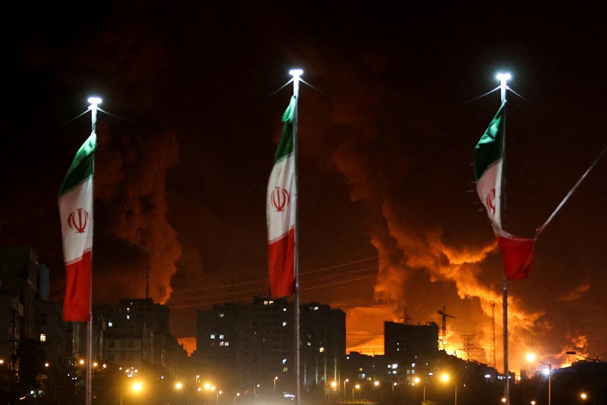 FILE PHOTO: Iranian flags fly as fire and smoke from an Israeli attack on Sharan Oil depot rise, following Israeli strikes on Iran, in Tehran, Iran, June 15, 2025. Majid Asgaripour/WANA (West Asia News Agency) via REUTERS   ATTENTION EDITORS - THIS PICTURE WAS PROVIDED BY A THIRD PARTY/File Photo