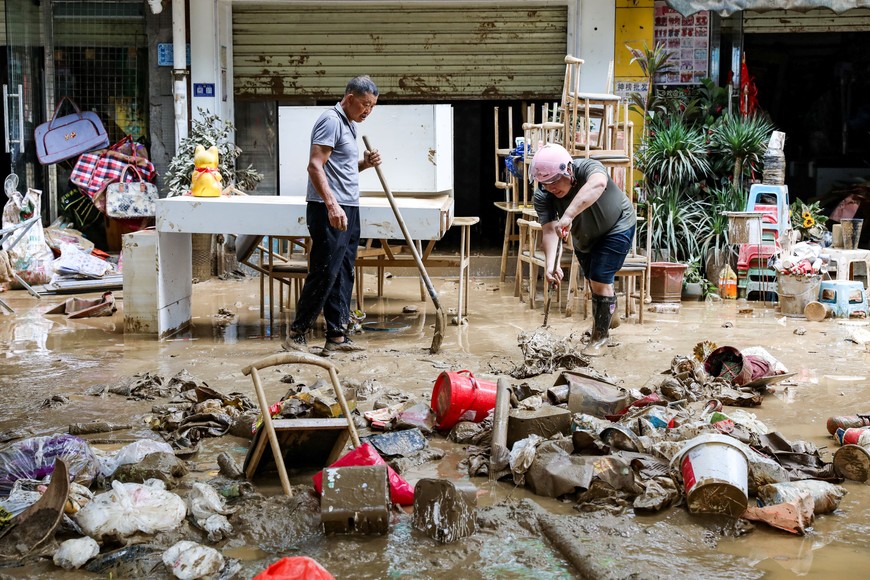 Residents clean up debris on a street after floodwaters receded in Rongjiang county, Guizhou province, China June 25, 2025. cnsphoto via REUTERS ATTENTION EDITORS - THIS IMAGE WAS PROVIDED BY A THIRD PARTY. CHINA OUT.