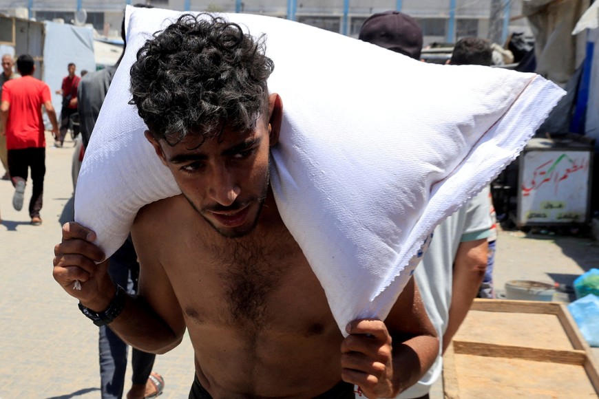 A Palestinian carries a sack of flour as people gather to receive aid supplies in Khan Younis, in the southern Gaza Strip, June 26, 2025. REUTERS/Hatem Khaled     TPX IMAGES OF THE DAY