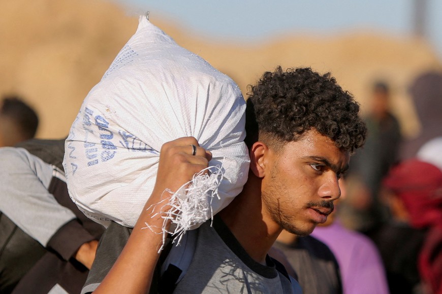 FILE PHOTO: A Palestinian carries a sack with aid supplies he received from the U.S.-backed Gaza Humanitarian Foundation, in Khan Younis, in the southern Gaza Strip, May 29, 2025. REUTERS/Hatem Khaled/File Photo