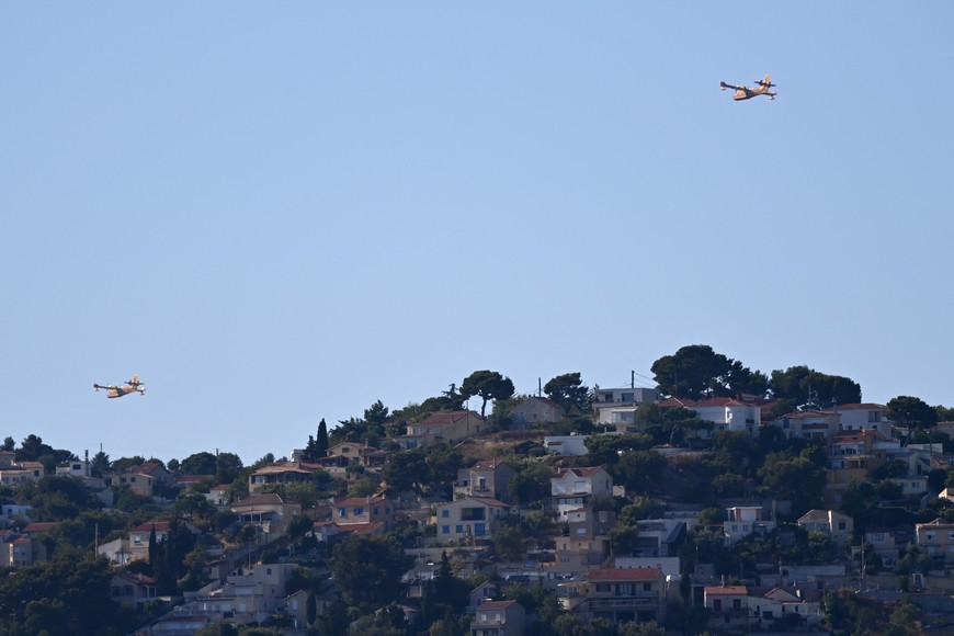 Canadair aerial firefighting aircafts fly over Marseille as a fast-moving wildfire spreads on the outskirts the city, southern France, July 8, 2025. REUTERS/Alexandre Dimou