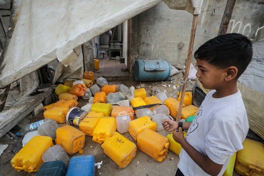 A Palestinian boy inspects the site of an Israeli strike that killed Palestinians, gathered to collect water from a distribution point, according to medics, in Nuseirat in the central Gaza Strip July 13, 2025. REUTERS/Stringer