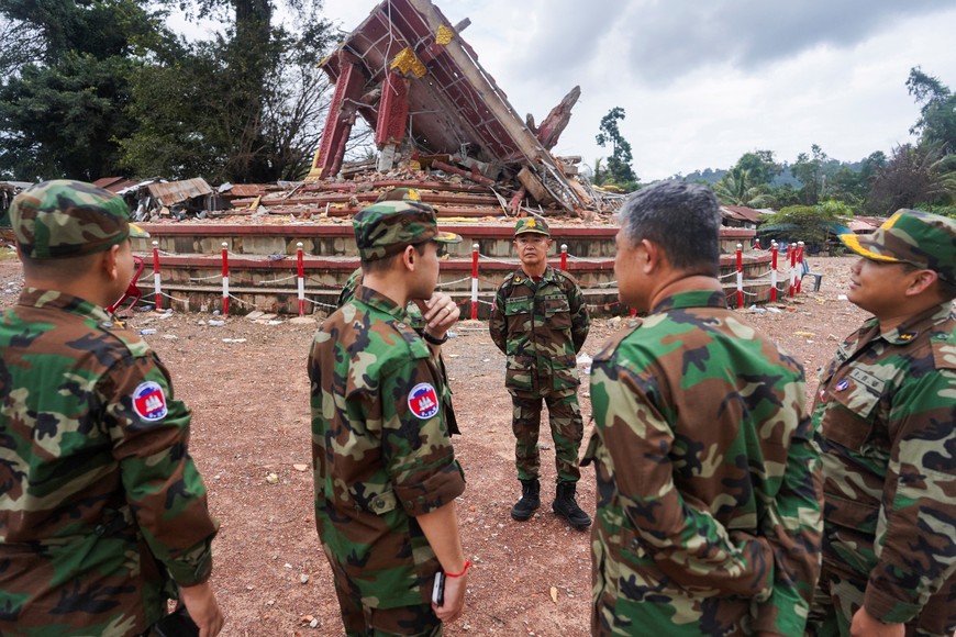 Military personnel stand near a destroyed monument at the closed An Ses border checkpoint, also known as Chong Arn Ma in Thai, during an inspection by foreign military attaches from major powers and ASEAN member countries, along with diplomats from 13 countries, after the leaders of Cambodia and Thailand agreed to a ceasefire on Monday effective midnight, in a bid to bring an end to their deadliest conflict in more than a decade, while Thailand's military accuses Cambodia of second ceasefire violation and wait for Cambodia’s invitation for bilateral talks on August 4, Cambodia, July 30, 2025. REUTERS/Soveit Yarn